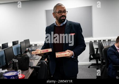 Home Secretary James Cleverly holds boxes of mince pies whilst meeting police officers at Luton Police Station to thank them for their service for working over the festive period. Picture date: Thursday December 21, 2023. Stock Photo