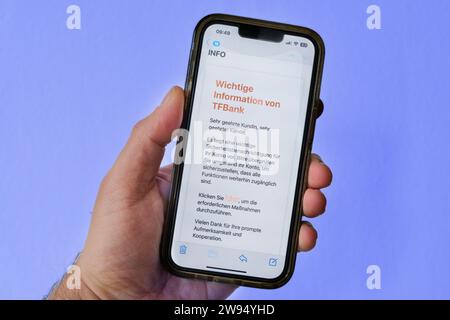 Hand holding a mobile phone showing an attempt at phishing by email, here a fake email from the Swedish TF Bank Stock Photo