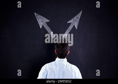 Businessman looking to a chalkboard with to arrows trying to decide one solution Stock Photo