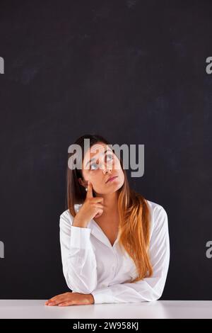 Woman thinking next to a blackboard Stock Photo