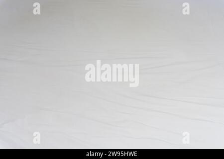 White crumpled or wrinkled bedding sheet or blanket with pattern after guest's use was taken in hotel, resort room with copy space. Untidy blanket bac Stock Photo