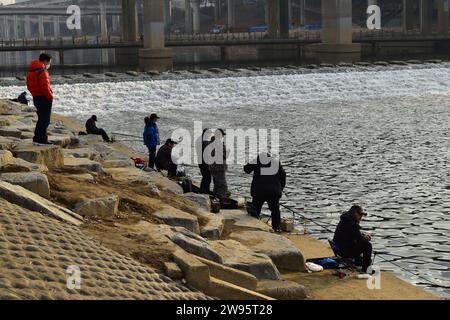 Local Korean men fishing in the turbulent water of a side river joining the river Han near the Olympic stadium Stock Photo