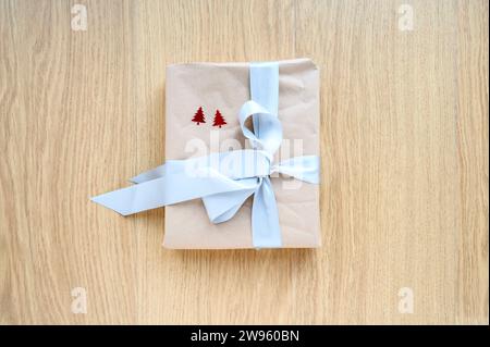 Christmas gift parcel wrapped in brown paper and tied up with a blue ribbon Stock Photo