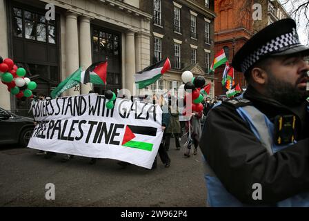 Protesters march around Soho Square behind a banner saying ’Sisters Stand With Gaza, Free Palestine’ during the demonstration. Sisters Uncut supporters gathered and marched in the West End shopping district of London in support of the Palestinians. They demanded for a permanent ceasefire in Gaza and for customers to boycott businesses that support Israel. Stock Photo