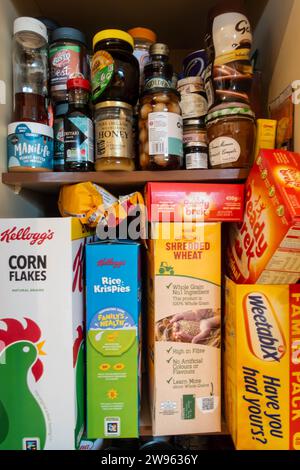 Foods of varying brands stored in a food cupboard bard in a kitchen Stock Photo