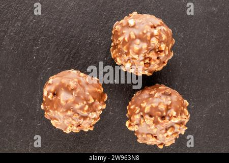 Several chocolates on a slate stone, macro, top view. Stock Photo