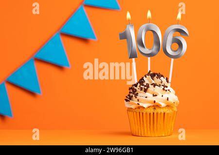 Birthday cake with candle number 106 - Orange background Stock Photo