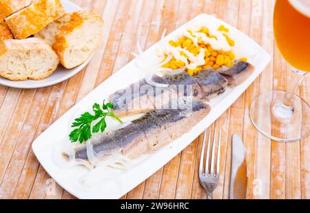 Sliced pickled herring fillet with corn and onions Stock Photo