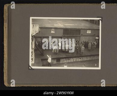 On the Kade, Anonymous, 1930 - 1931 photograph Album magazine with a photo of a group of people waiting for the quay. Part of photo album 'Student album Indologists'. Netherlands photographic support. cardboard gelatin silver print pier, quay, wharf Netherlands Stock Photo