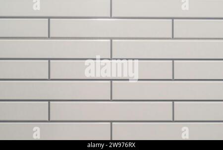 Small white tiled wall with beautiful horizontal pattern is used for background or texture in decorative art work or template. Stock Photo