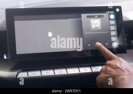 Close up photo, driiver's forefinger is touching flat screen player to turn on music while driving super modern car. Concept of using high technology Stock Photo