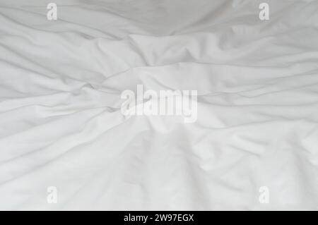 White crumpled or wrinkled bedding sheet or blanket with pattern after guest's use was taken in hotel, resort room with copy space. Untidy blanket bac Stock Photo