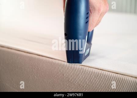Worker stapling sofa lining with electric staple gun Stock Photo