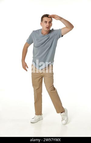 young man looking far away at distance with hand over head on white background Stock Photo