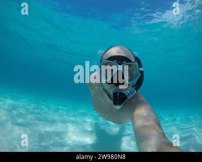 A man wearing a pair of swimming goggles on his head while swimming in the ocean Stock Photo