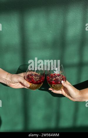 Hands holding cocktail glasses against green backdrop Stock Photo