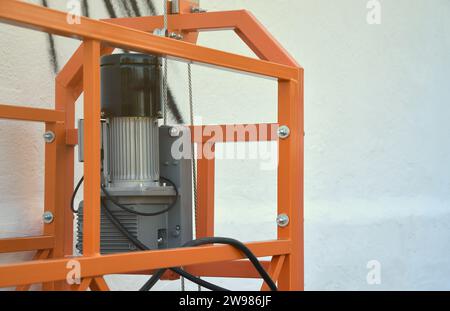 Hoist supply and safety lock as part of suspended wire rope platform for facade works on high multistorey buildings. Hoist for elevation, raising or lifting cradle platform Stock Photo