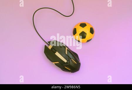 Soccer ball with computer mouse on violet background. Concept of videogames, eSports, sports betting and online gambling Stock Photo