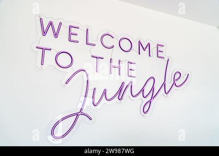 a purple neon welcome to the jungle wall sign on a white wall Stock Photo