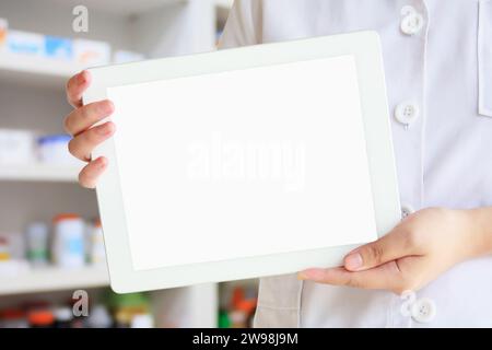 Female pharmacist showing tablet computer over pharmacy drugstore background Stock Photo