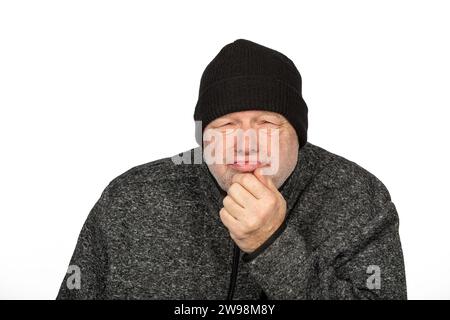 Contemplative Middle-Aged Worker in Black Winter Hat on White Background Feeling the Cold Stock Photo