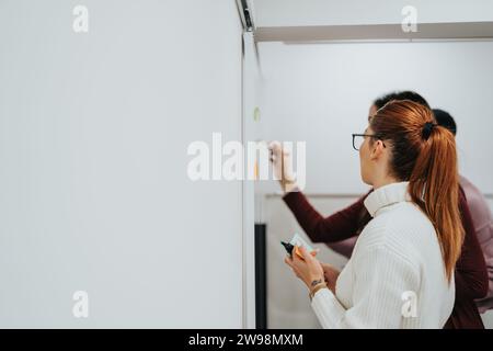 Creative team collaboration in corporate office for business success. Writing on sticky notes and glass wall, sharing ideas for teamwork and success. Stock Photo