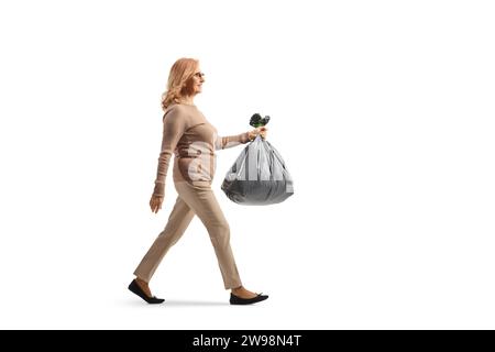 Full length profile shot of a middle aged woman carrying a plastic waste bag isolated on white background Stock Photo