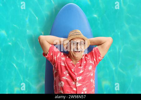 Happy mature man lying on a surfing board in the water and smiling Stock Photo