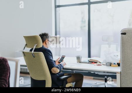 Middle-aged businessman sitting in a comfy chair checking his email during break at work. Stock Photo