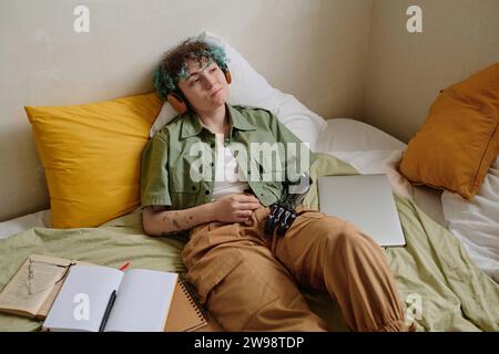 Relaxed girl with prosthetic arm listening to audiobook in headphones Stock Photo