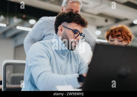 Creative professionals collaborating in a modern office, using technology for market analysis and discussing financial planning for business expansion Stock Photo