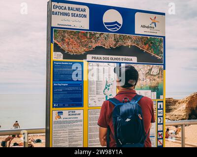 A young man standing in front of a sign in Algarve, Portugal. Stock Photo