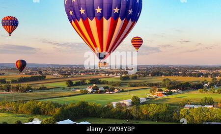 A vibrant array of multicolored balloons drift high above a residential area Stock Photo