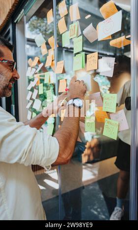 Multiracial Team Discussing Ideas and Writing on Sticky Notes in Modern Office Stock Photo