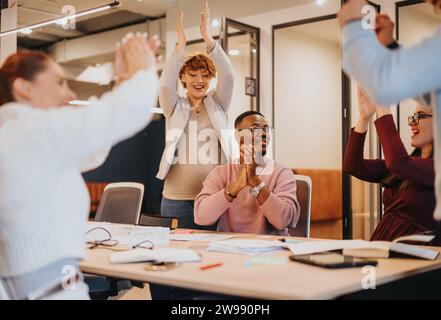 Diverse office team celebrates successful project with smiles and joy. Stock Photo