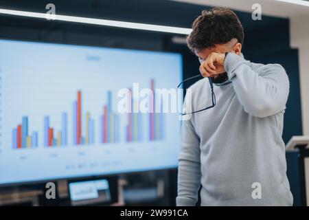 Tired, male, business employee holding eyeglasses rubbing his eyes after rough working day at the office. Copy space. Stock Photo