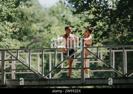A couple trains outdoors, doing exercises on a bridge. They're determined and motivated, enjoying the sunny weather and fresh air. Stock Photo