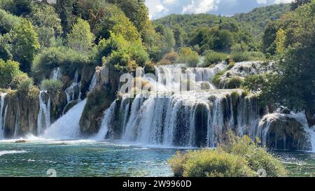 A scenic view of a waterfall surrounded by lush, green vegetation Stock Photo