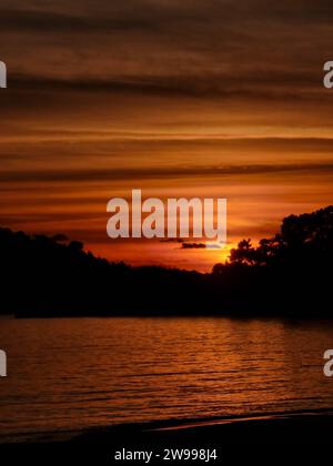 A breathtaking sunset is seen over the horizon of the ocean with a large vessel sailing in the scenic background Stock Photo