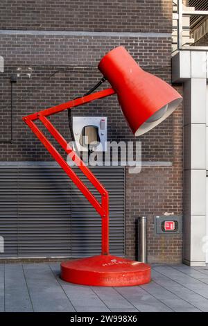 A red vintage-style lantern hanging on the wall of a brick building with its lampshade closed Stock Photo