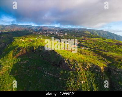 Aerial view of a beautiful vibrant landscape featuring a lush green valley with a small residential area located in the Madeira region Stock Photo