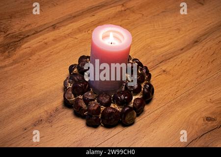 The decorative pinky candle with flame on chestnut ring on close-up christmas scene Stock Photo