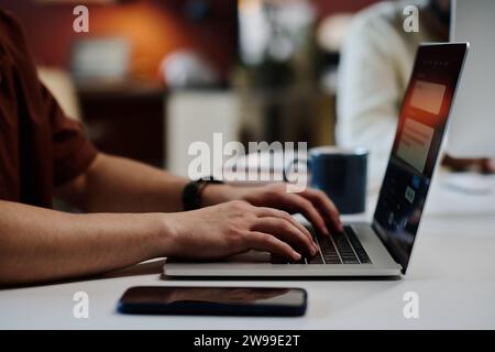 Hands of young unrecognizable businessman typing on laptop keyboard while carrying out AI design task or working over new project Stock Photo