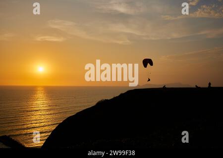 A scenic view of people paragliding at sunset in Lima Stock Photo