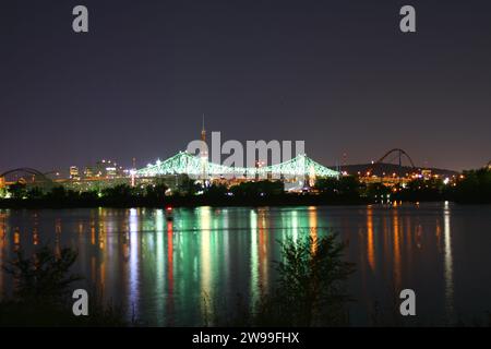 An illuminated city skyline at night, with the bright lights reflecting off the waters of a river below Stock Photo