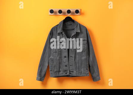 Hanger with dark gray denim jacket on orange wall Stock Photo