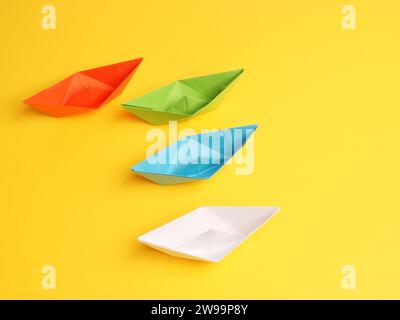 Four different paper boats on a yellow background, teamwork concept Stock Photo