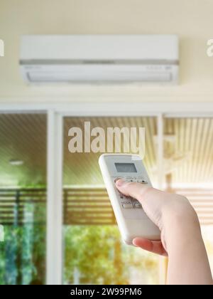 Hand hold remote control directed on the air conditioner Stock Photo