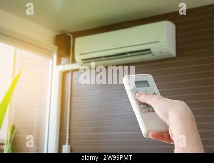 Hand hold remote control directed on the air conditioner Stock Photo