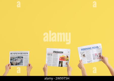 Women with newspapers on yellow background Stock Photo